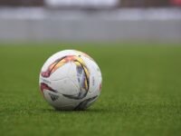 Bola de futebol sobre o gramado de um campo